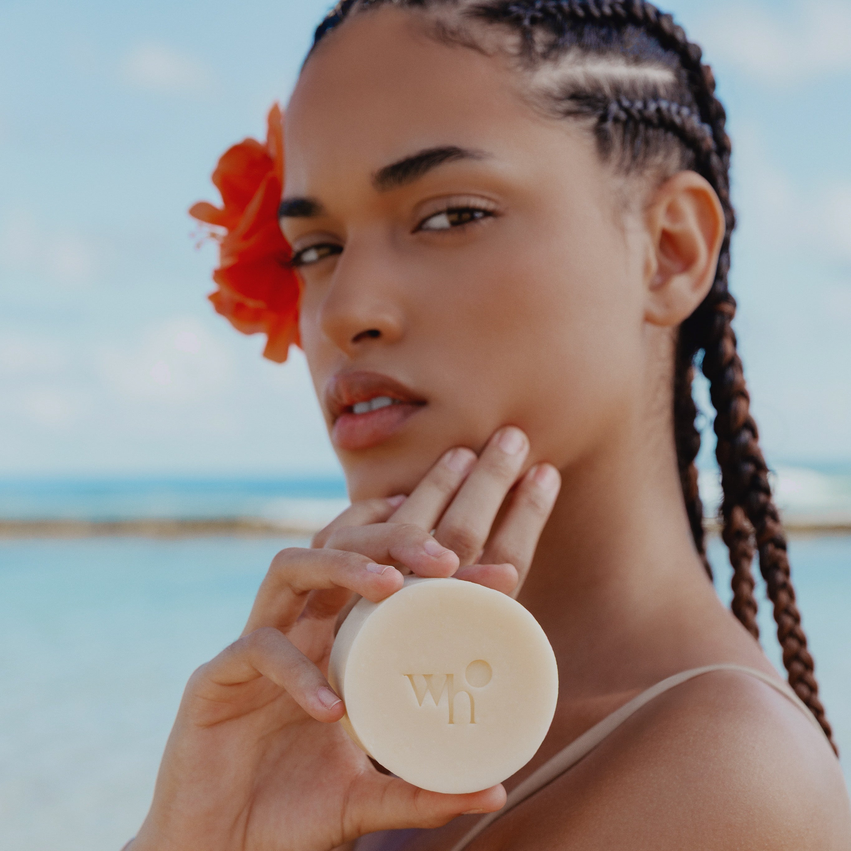 Woman on the beach holding a white soap  which is our eighty percent olive oil soap